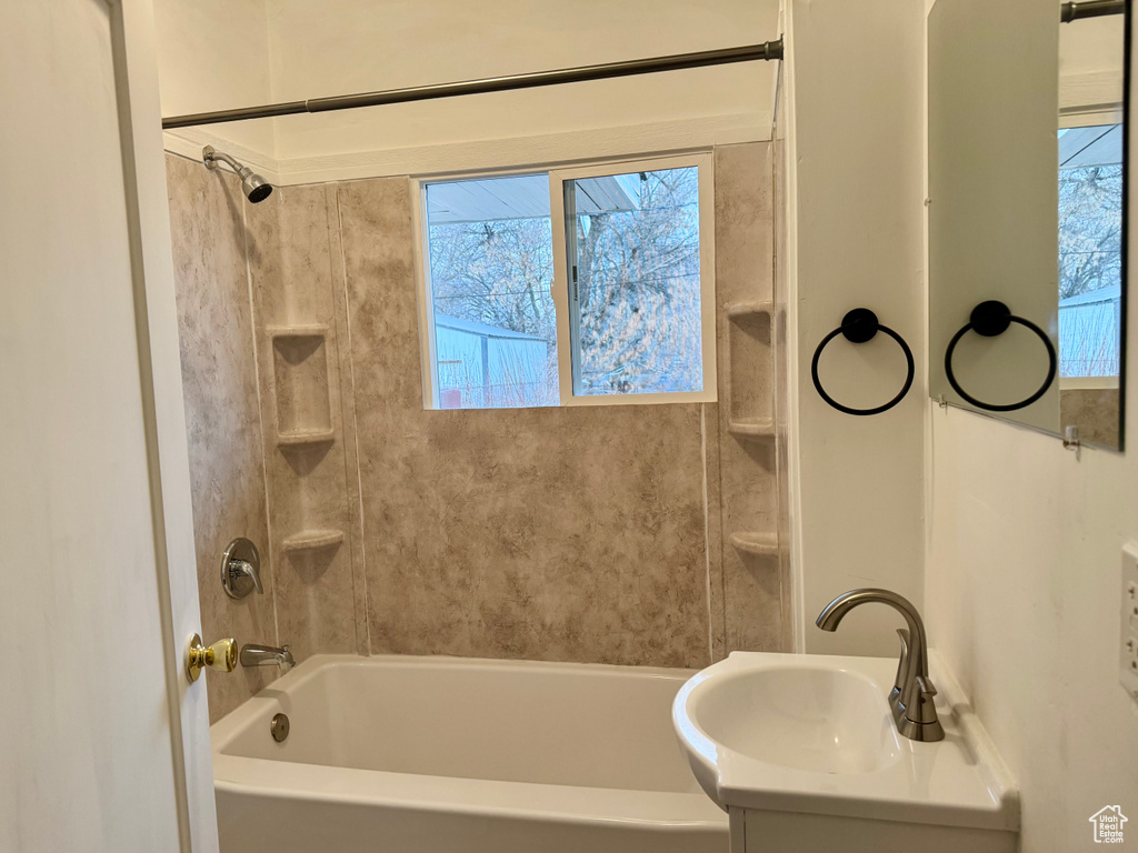 Bathroom featuring tiled shower / bath, vanity, and a wealth of natural light