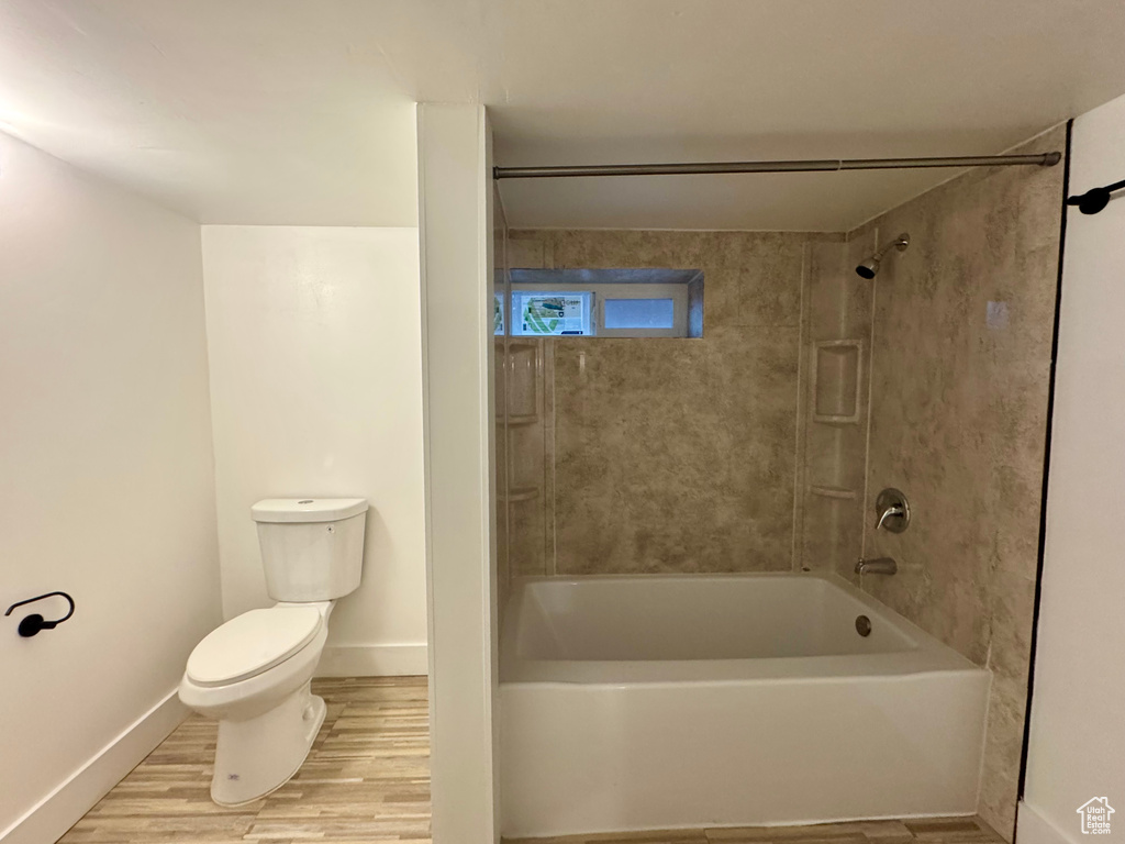 Bathroom featuring hardwood / wood-style flooring, tiled shower / bath, and toilet