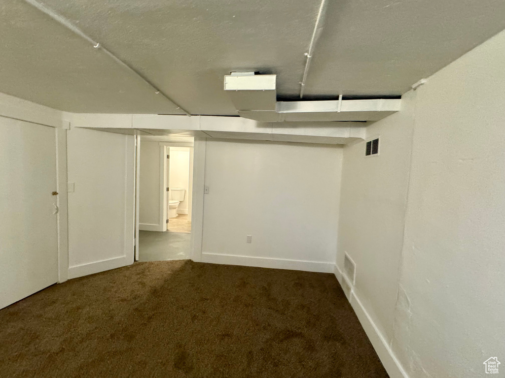 Basement featuring dark colored carpet and a textured ceiling