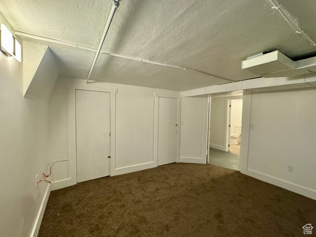 Basement with dark carpet and a textured ceiling