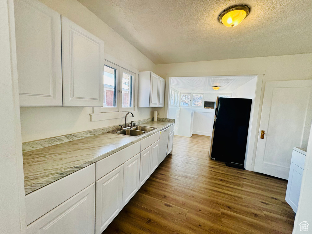 Kitchen with white cabinetry, dark wood finished floors, light countertops, a textured ceiling, and a sink