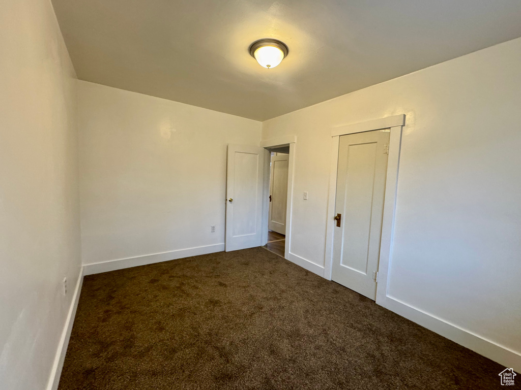 Unfurnished bedroom featuring dark carpet