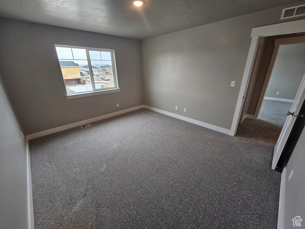 Carpeted spare room featuring a textured ceiling