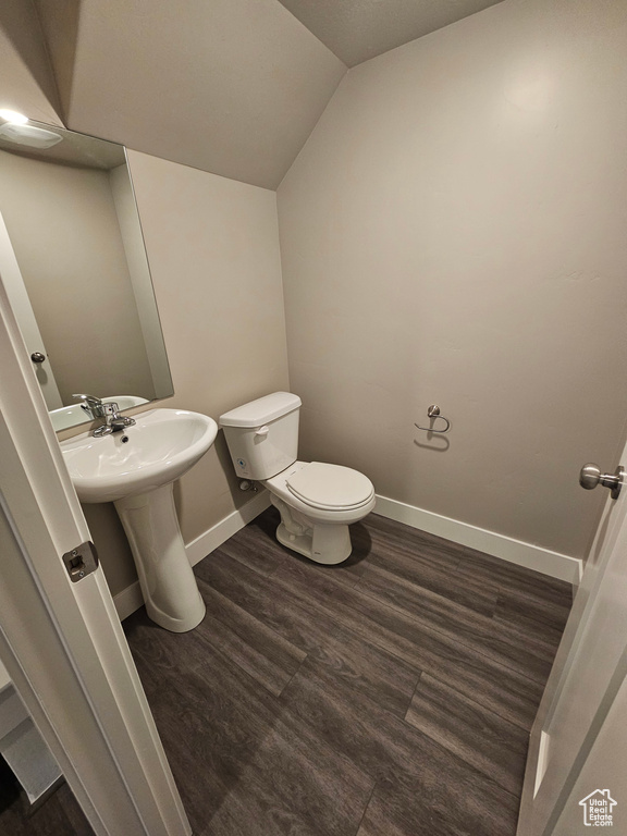 Bathroom with hardwood / wood-style flooring, vaulted ceiling, sink, and toilet