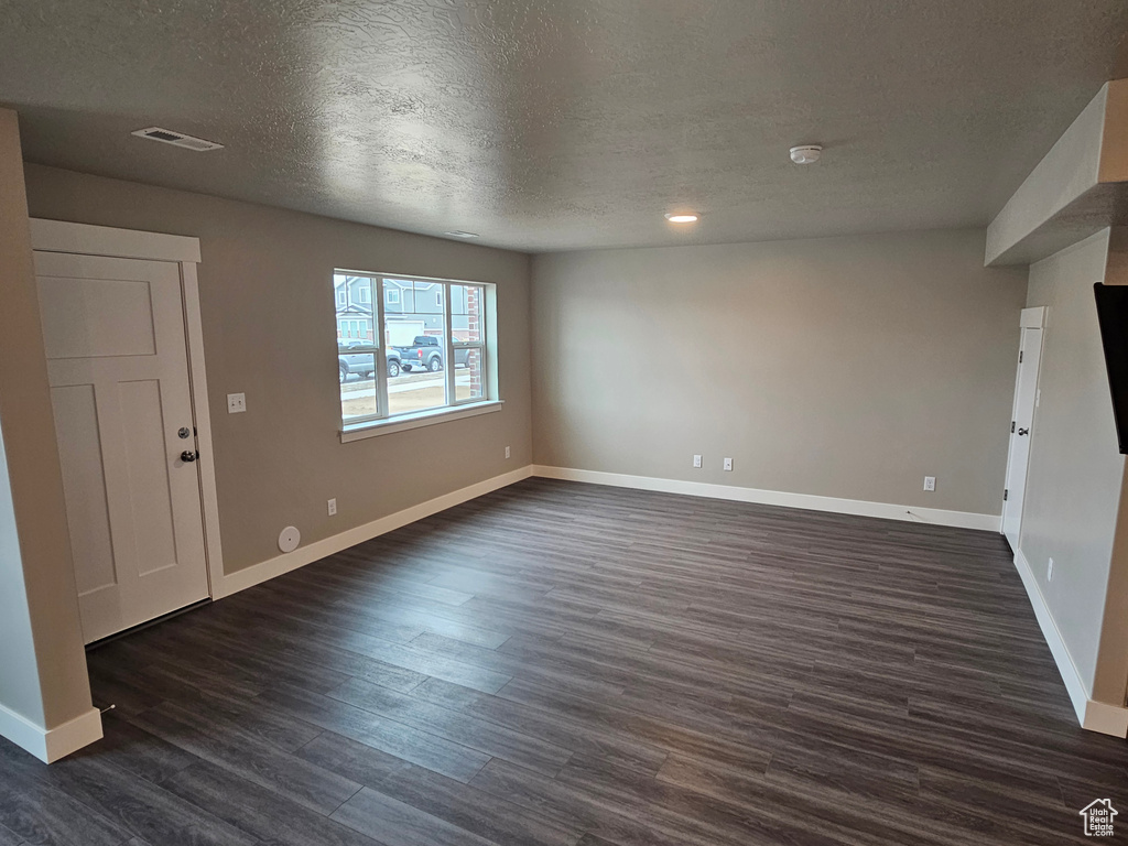 Unfurnished living room with dark hardwood / wood-style flooring and a textured ceiling