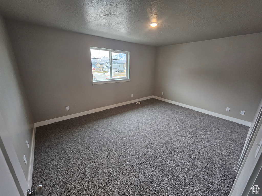 Empty room featuring a textured ceiling and carpet