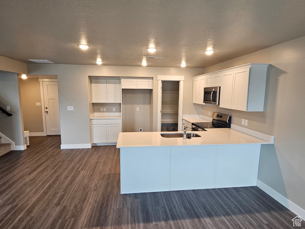 Kitchen with sink, appliances with stainless steel finishes, white cabinetry, a textured ceiling, and dark hardwood / wood-style flooring