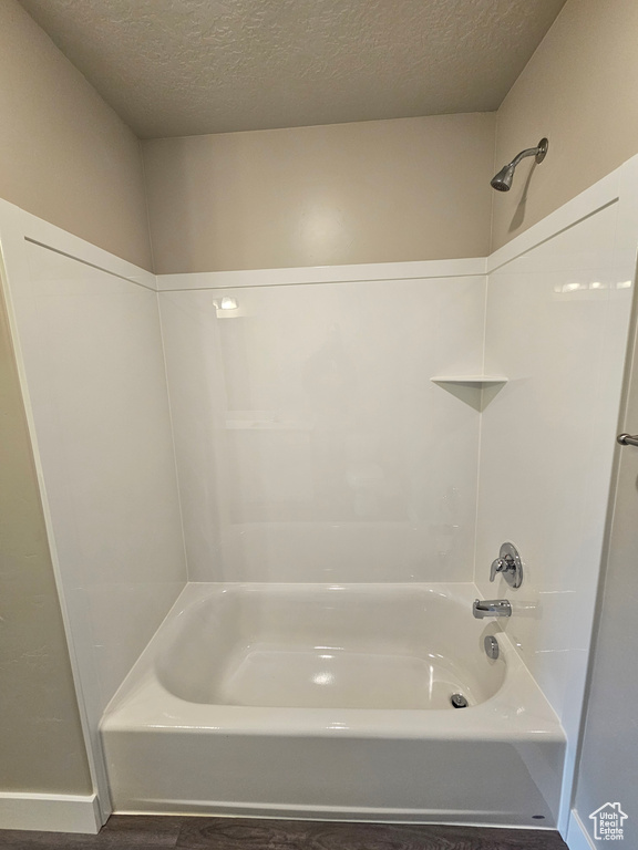 Bathroom with shower / washtub combination and a textured ceiling