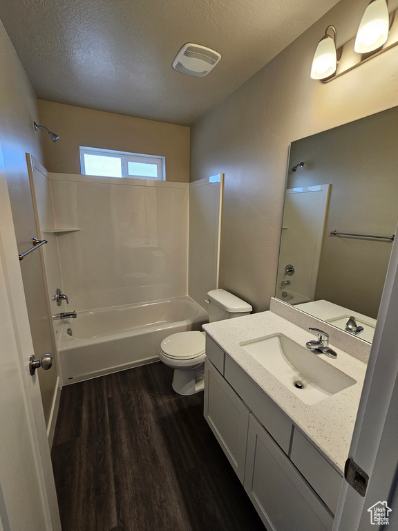 Full bathroom with shower / bathtub combination, hardwood / wood-style flooring, vanity, toilet, and a textured ceiling