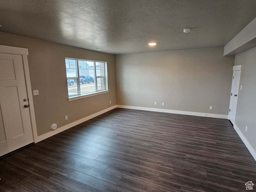 Spare room featuring dark wood-type flooring and a textured ceiling