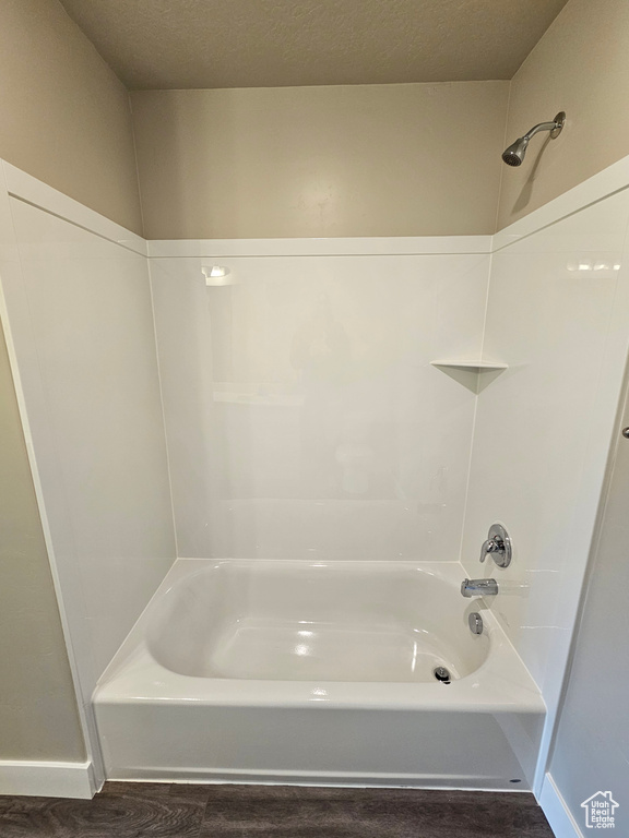 Bathroom featuring wood-type flooring, a textured ceiling, and shower / bath combination