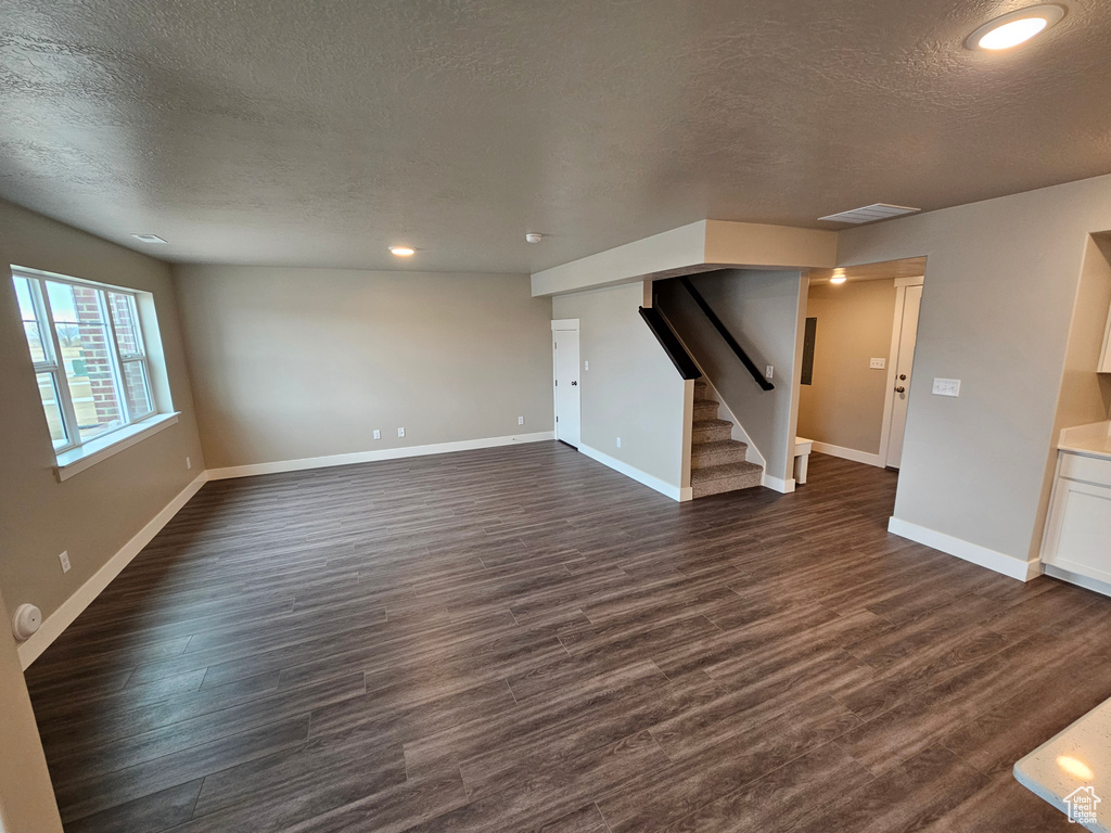 Unfurnished living room featuring dark hardwood / wood-style floors and a textured ceiling