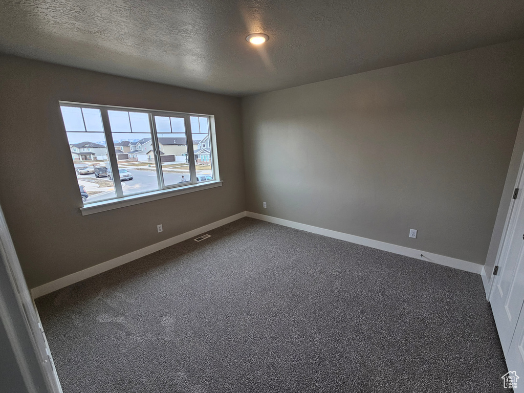 Empty room with carpet flooring and a textured ceiling