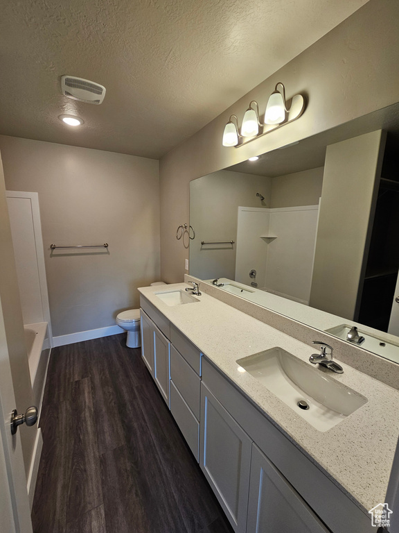 Bathroom featuring vanity, toilet, hardwood / wood-style floors, and a textured ceiling