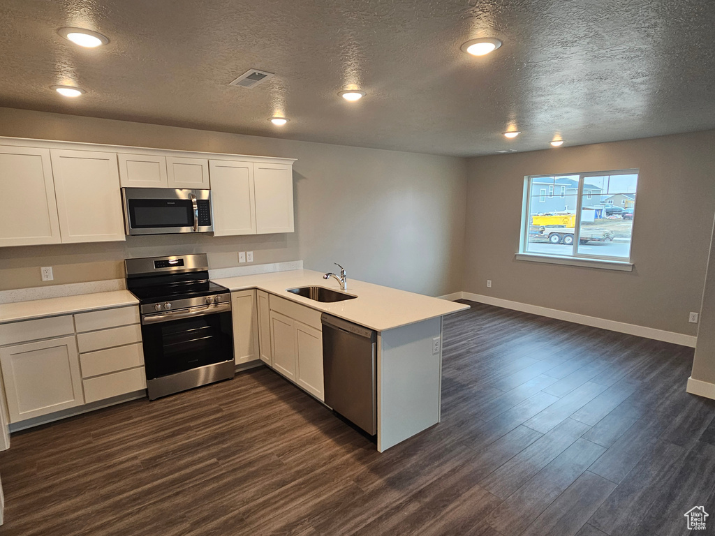 Kitchen with white cabinetry, sink, kitchen peninsula, and appliances with stainless steel finishes