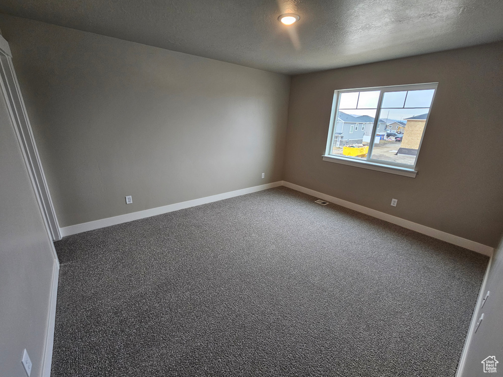 Carpeted spare room featuring a textured ceiling