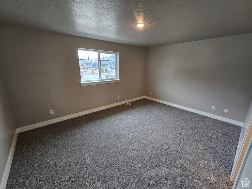 Spare room featuring carpet floors and a textured ceiling