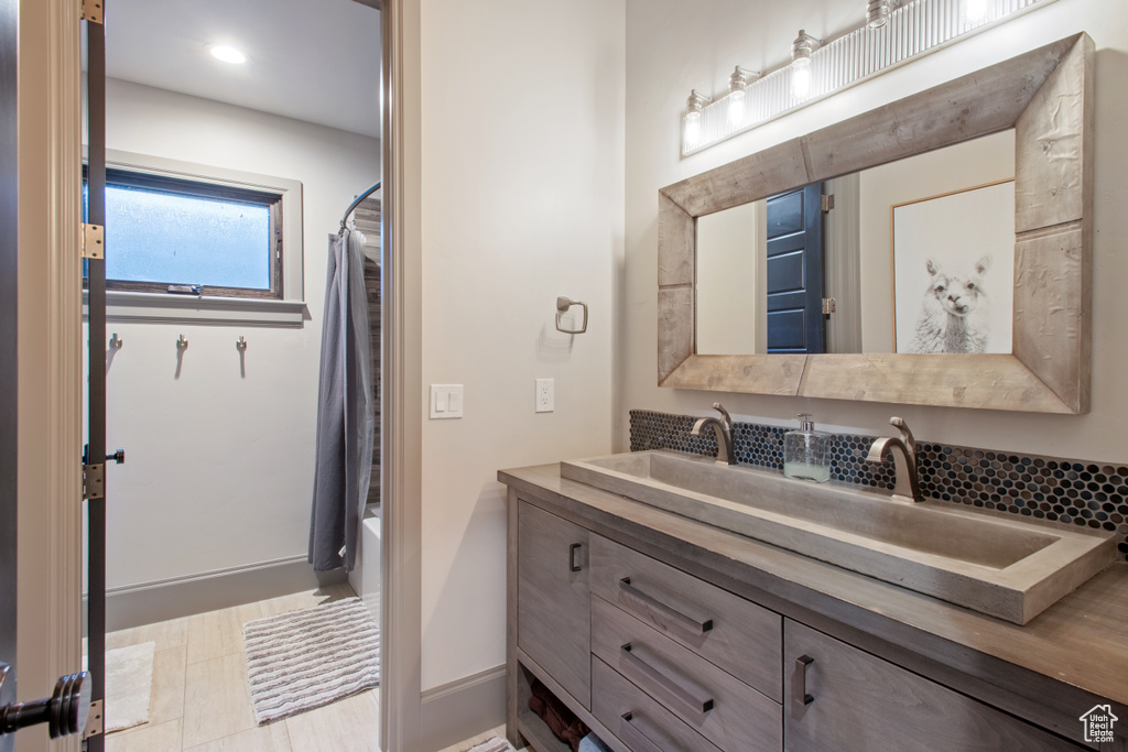 Bathroom with vanity, shower / bath combination with curtain, and decorative backsplash