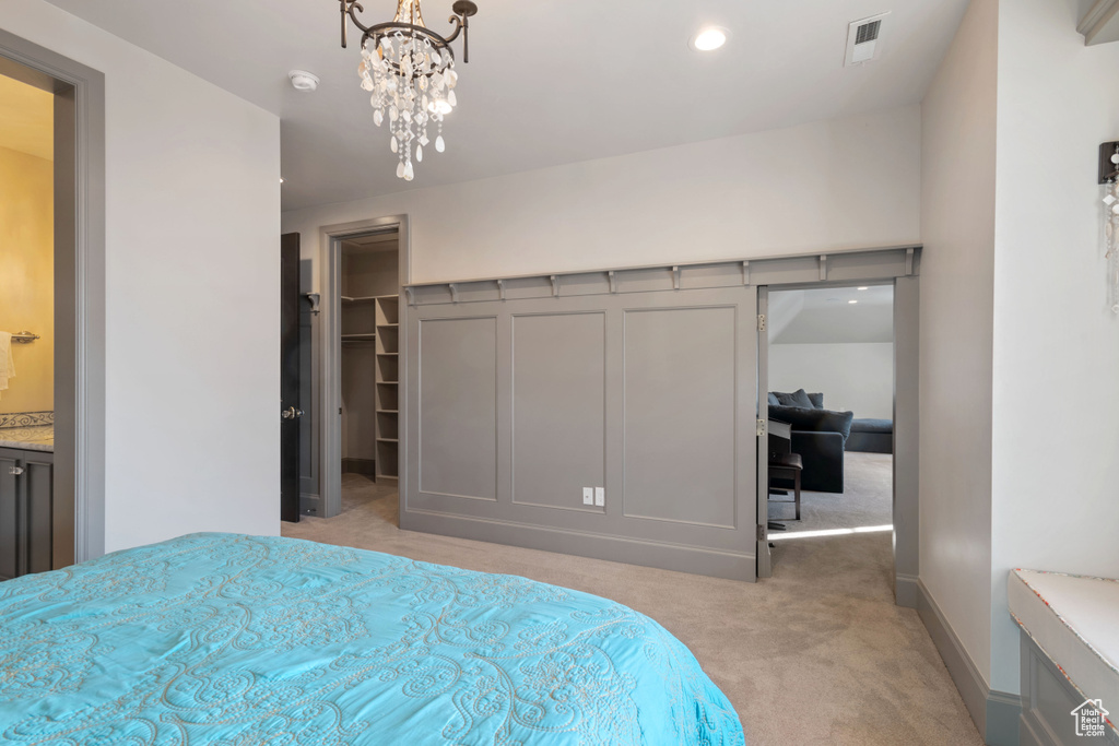 Carpeted bedroom with an inviting chandelier and a walk in closet