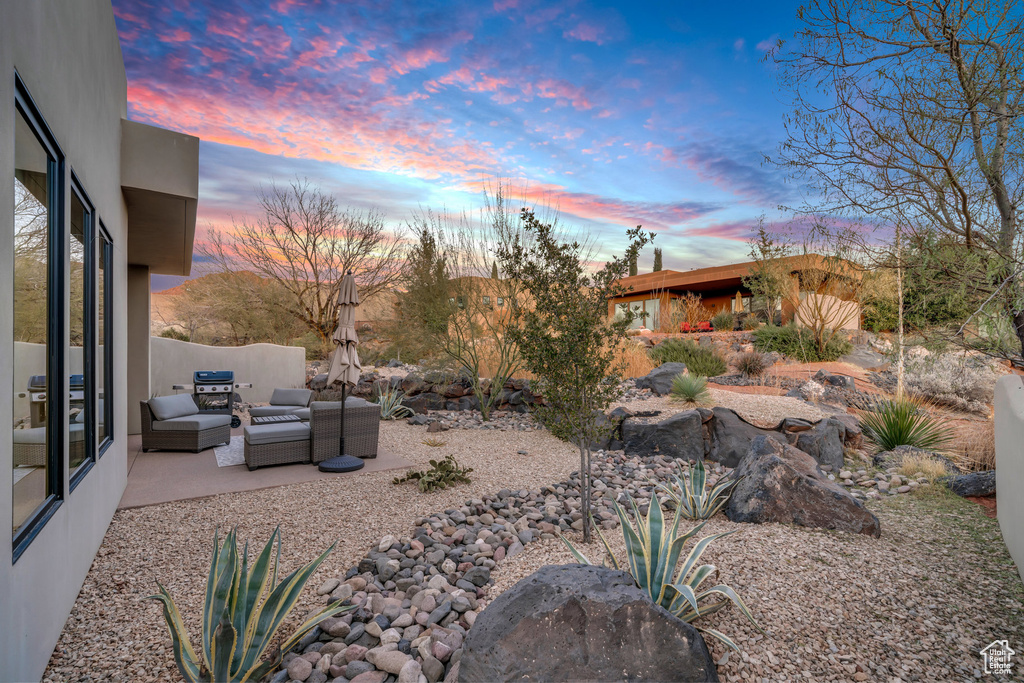 Yard at dusk with outdoor lounge area and a patio