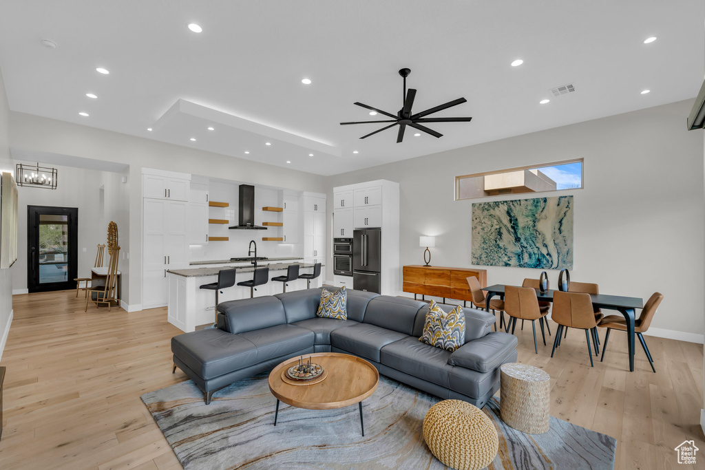 Living room with sink, ceiling fan with notable chandelier, and light hardwood / wood-style flooring