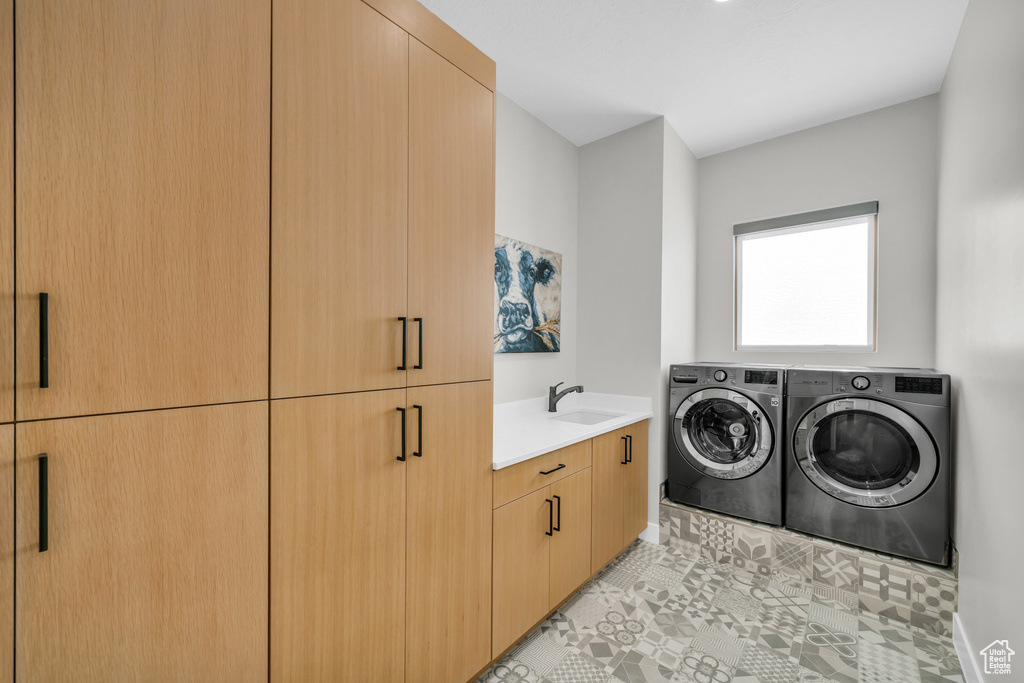 Laundry area with sink, washer and clothes dryer, and cabinets