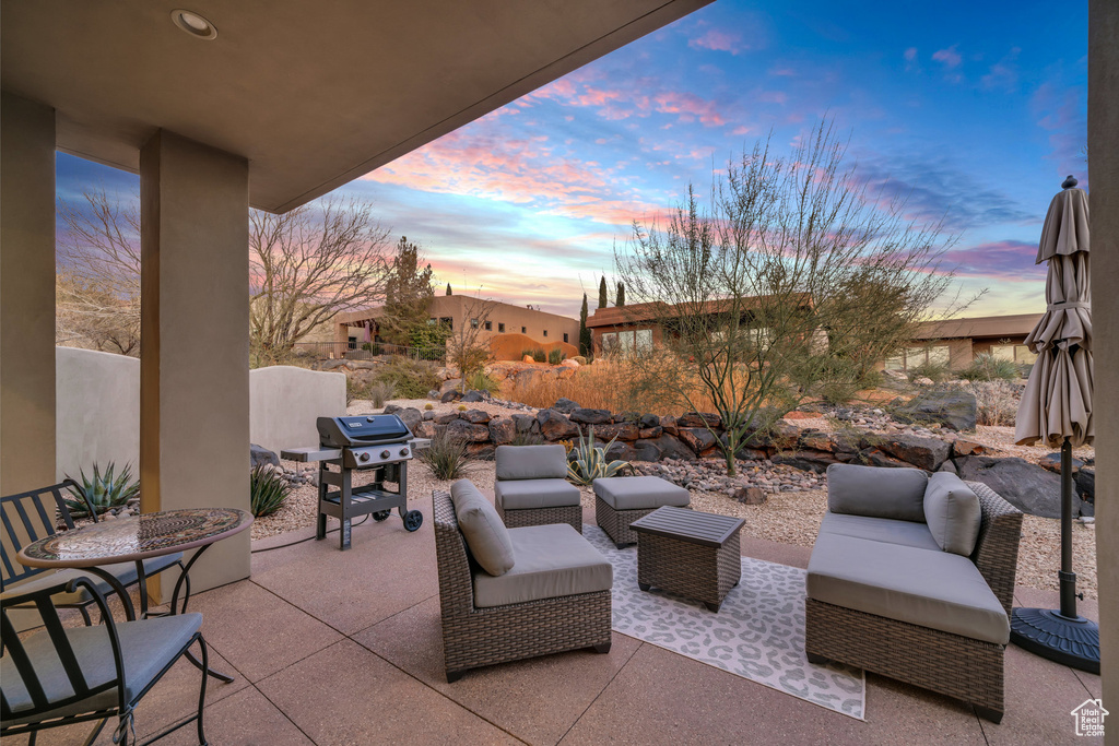 Patio terrace at dusk featuring outdoor lounge area and a grill