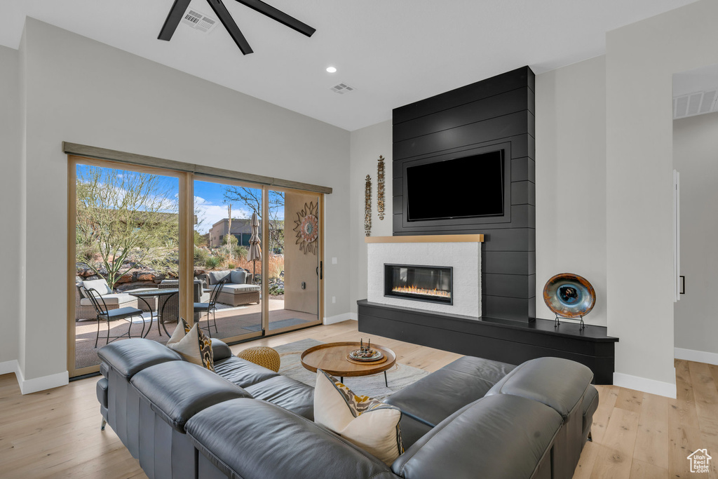 Living room featuring ceiling fan, a fireplace, and light hardwood / wood-style flooring