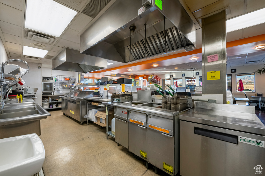 Kitchen featuring a drop ceiling, sink, range hood, and dishwasher
