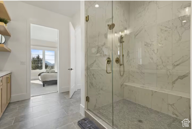 Bathroom with a marble finish shower, ensuite bath, vanity, and baseboards