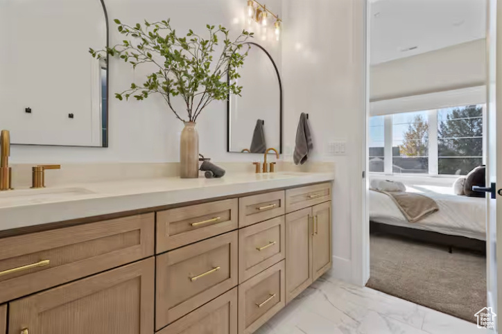 Bathroom with marble finish floors, double vanity, and ensuite bath