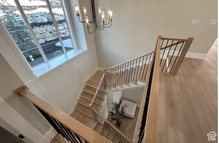 Stairway with a chandelier, wood finished floors, and baseboards