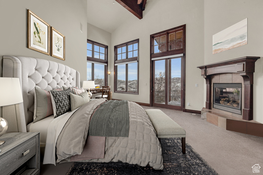 Carpeted bedroom featuring access to exterior, high vaulted ceiling, a tile fireplace, and multiple windows
