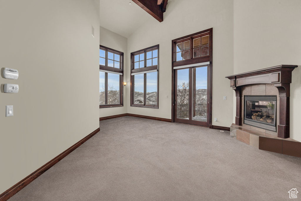 Unfurnished living room featuring high vaulted ceiling, carpet floors, a fireplace, and healthy amount of natural light