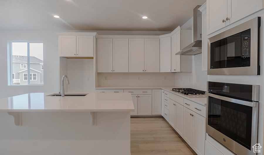 Kitchen featuring gas stovetop, built in microwave, a sink, stainless steel oven, and wall chimney exhaust hood