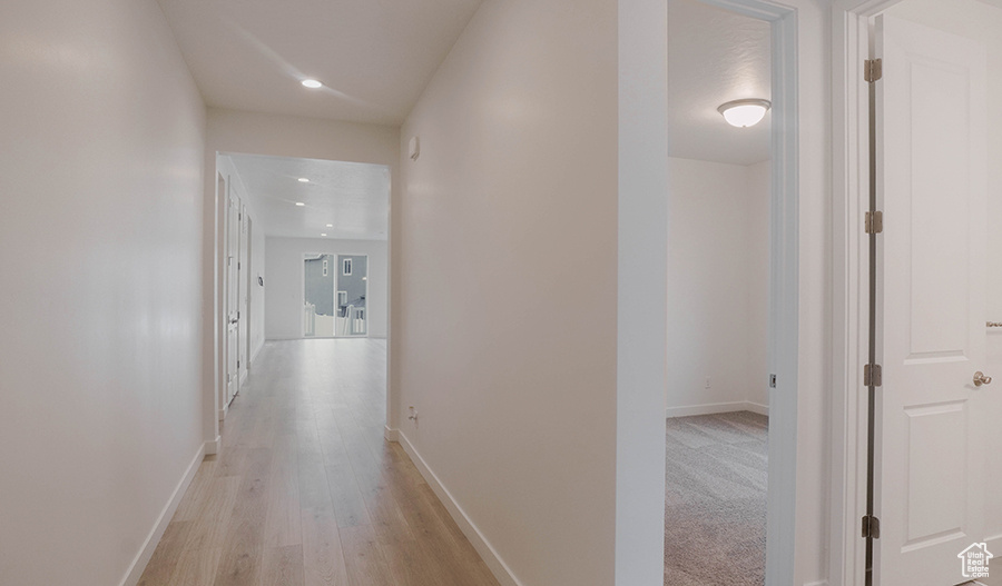 Corridor with light wood-style flooring and baseboards