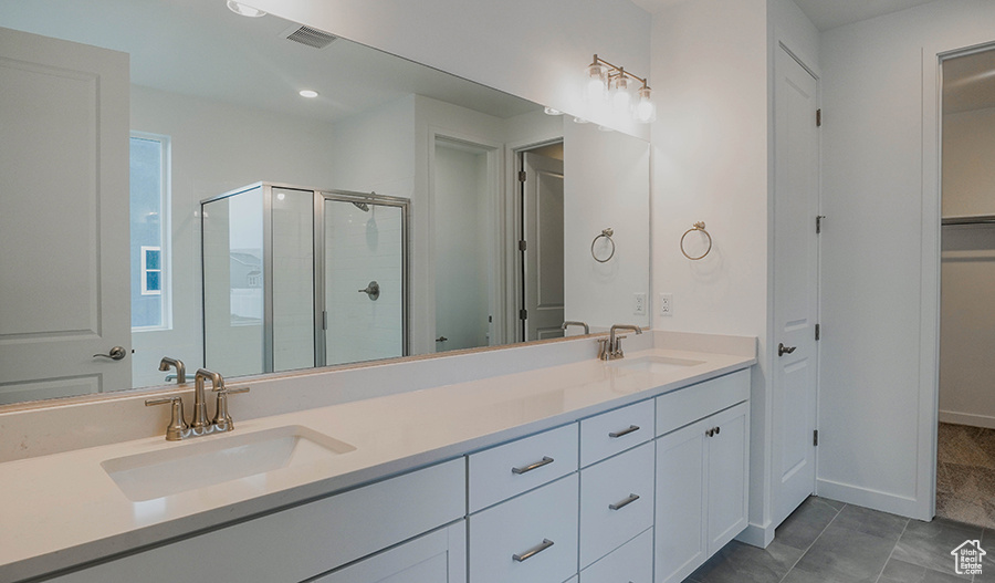 Bathroom with double vanity, visible vents, a shower stall, and a sink
