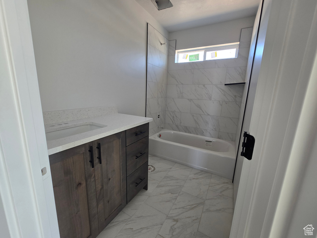 Full bath featuring marble finish flooring, washtub / shower combination, and vanity