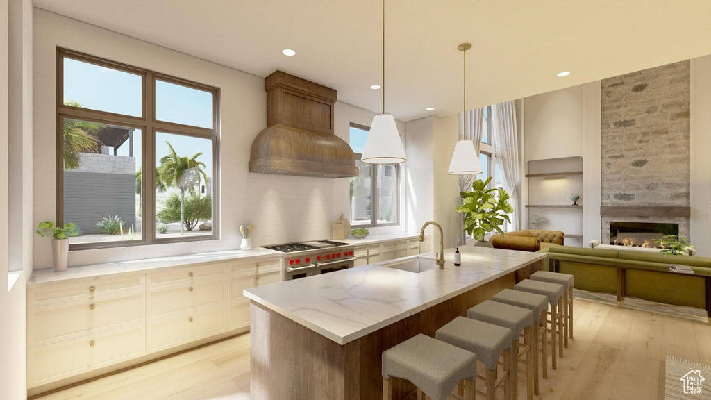 Kitchen featuring sink, double oven range, custom range hood, pendant lighting, and light hardwood / wood-style floors