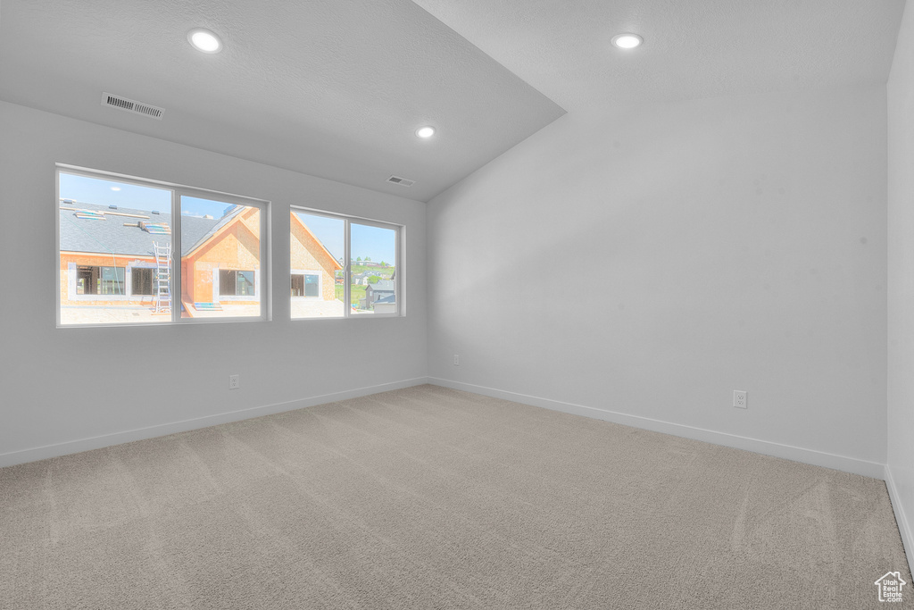 Empty room with lofted ceiling and carpet