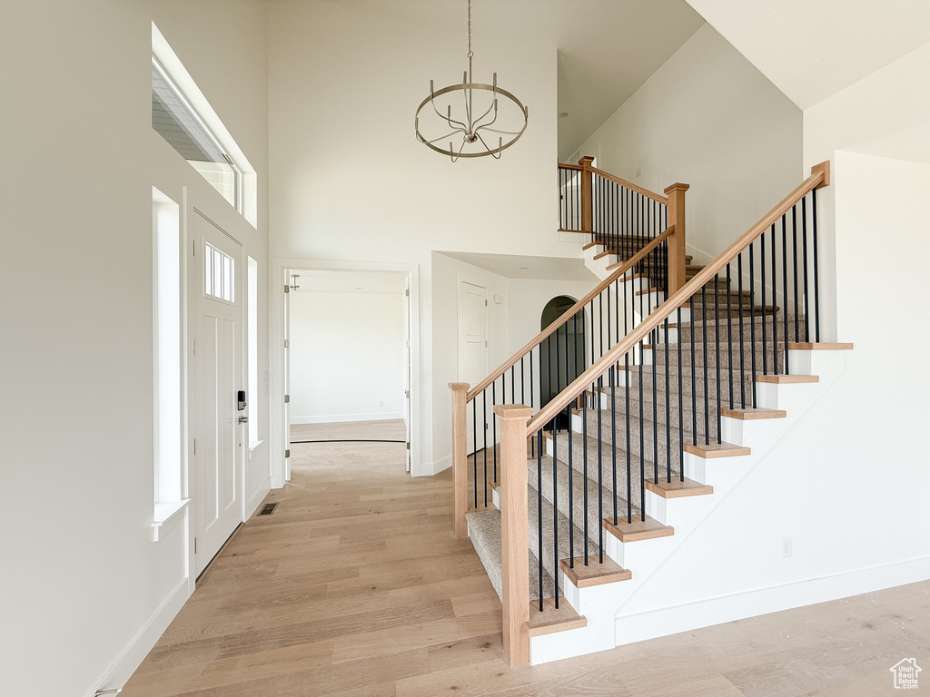 Entryway featuring a towering ceiling, a chandelier, wood finished floors, and stairway
