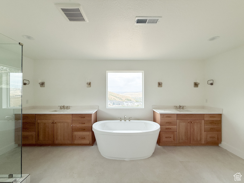 Bathroom featuring two vanities, a stall shower, and a freestanding bath