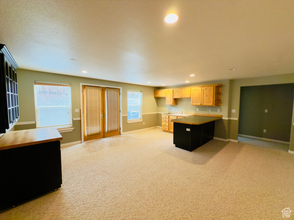 Kitchen featuring light brown cabinets, open shelves, light carpet, recessed lighting, and a peninsula