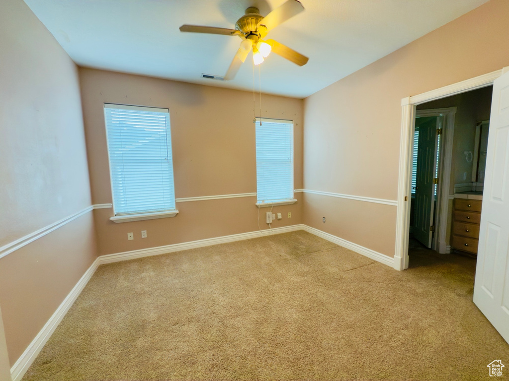 Carpeted spare room featuring ceiling fan and baseboards