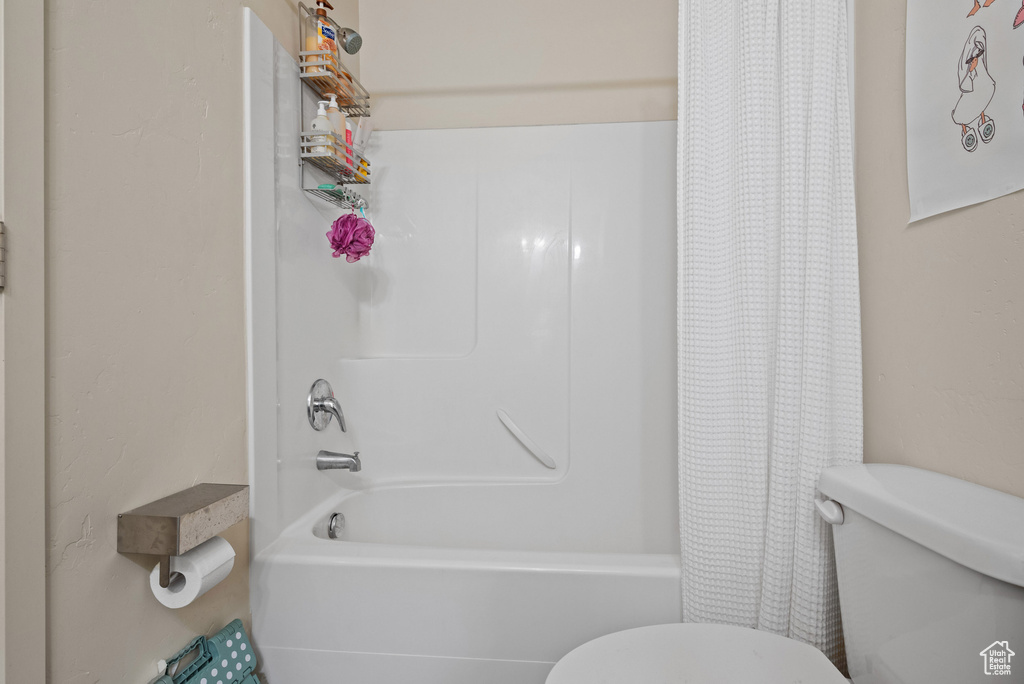 Full bathroom featuring toilet and shower / bath combo with shower curtain