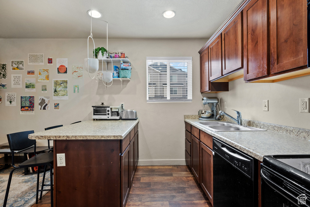 Kitchen featuring a kitchen breakfast bar, light countertops, dark wood-type flooring, a sink, and dishwasher