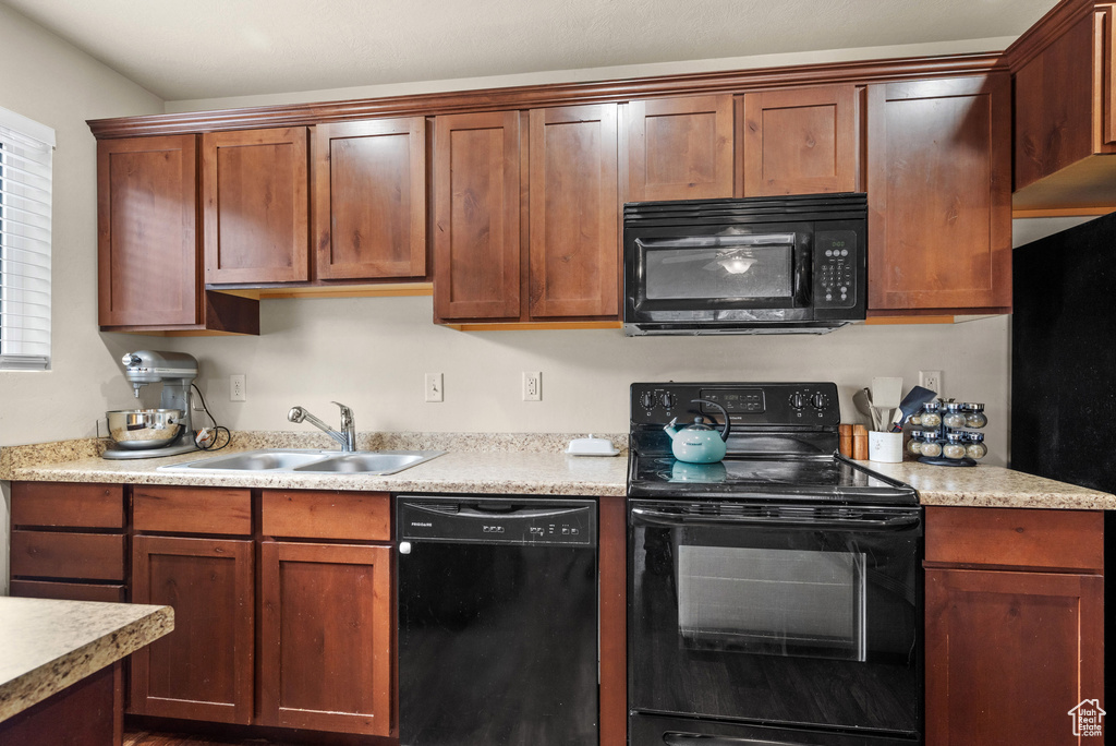 Kitchen featuring black appliances, light countertops, and a sink