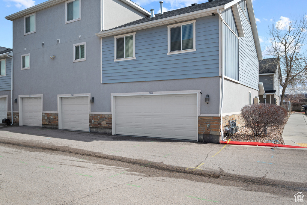 Back of house featuring stone siding and a garage