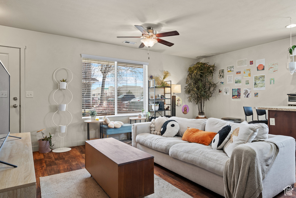 Living area with a ceiling fan, dark wood-style floors, and visible vents