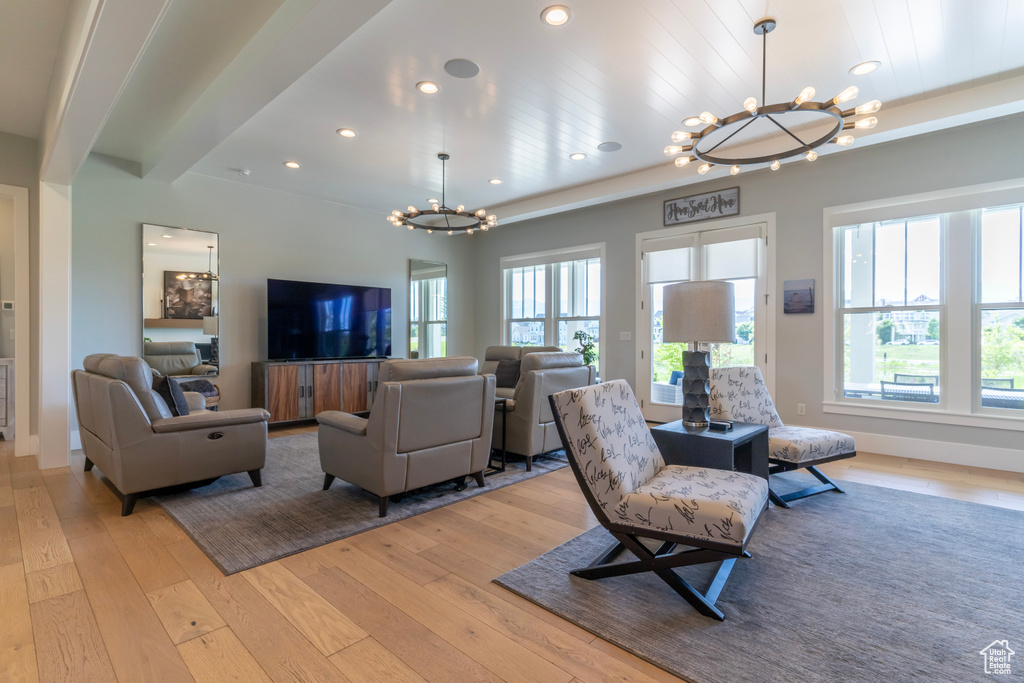 Living room with beam ceiling, a wealth of natural light, a chandelier, and light hardwood / wood-style flooring